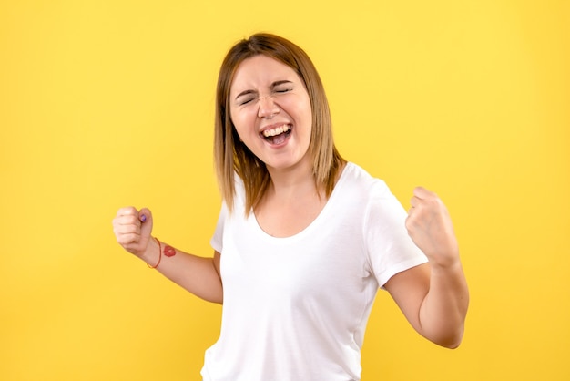 Front view of young woman rejoicing on yellow wall