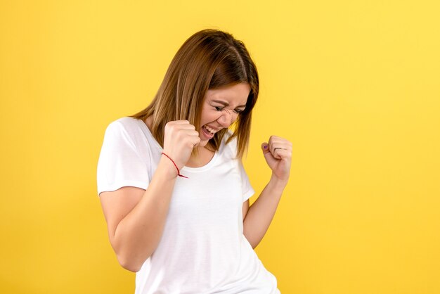 Front view of young woman rejoicing on yellow wall