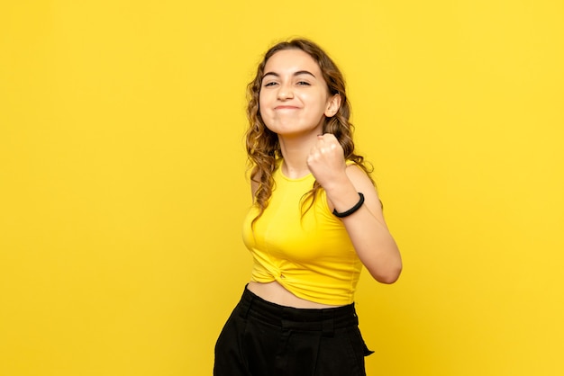 Front view of young woman rejoicing on yellow wall