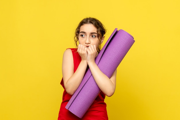 Front view of young woman scared with purple carpet on yellow wall