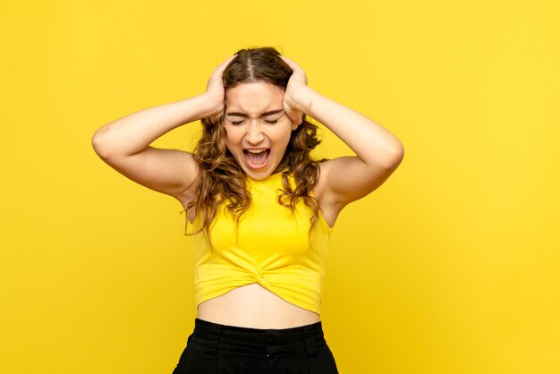 Front view of young woman screaming on a yellow wall