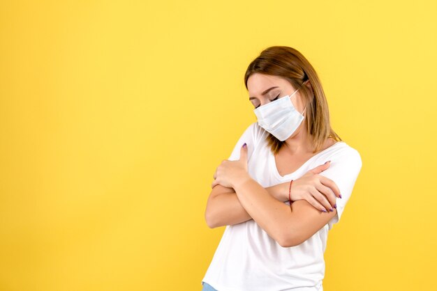 Front view of young woman shivering on yellow wall