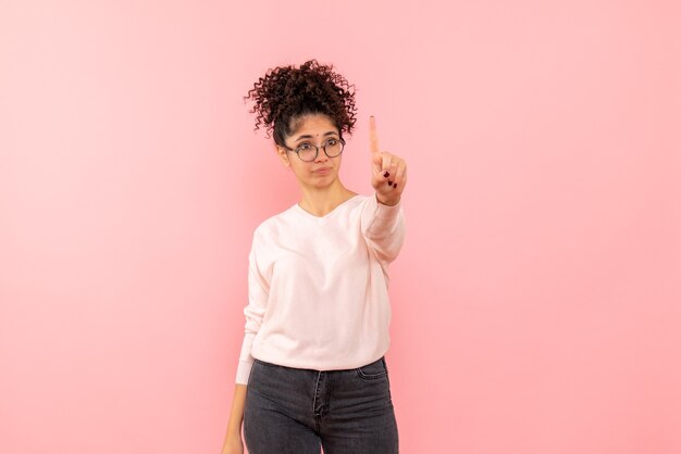 Front view of young woman showing number on pink wall