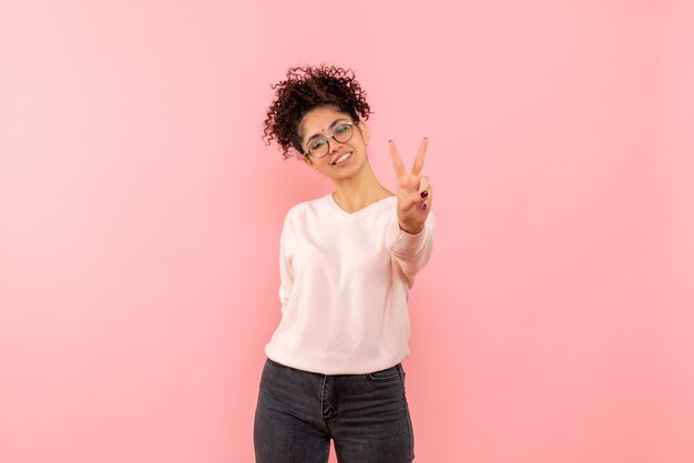 Front view of young woman showing number on pink wall