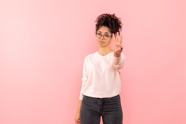 Front view of young woman showing number on pink wall