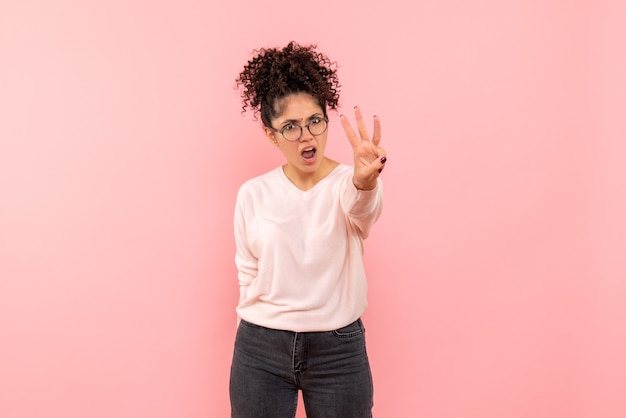 Free photo front view of young woman showing number on pink wall