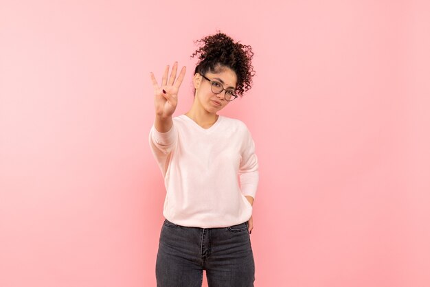 Front view of young woman showing number on a pink wall