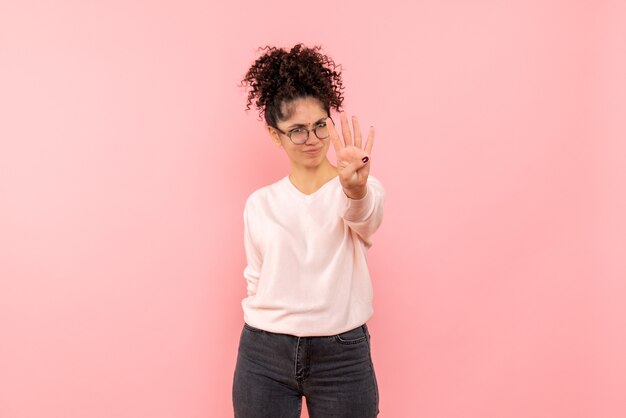 Front view of young woman showing number on pink wall