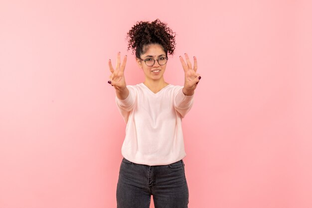 Front view of young woman showing number on pink wall