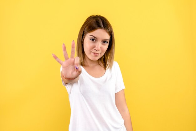 Front view of young woman showing number on yellow wall