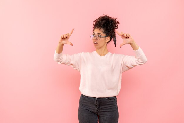 Front view of young woman showing size on pink wall