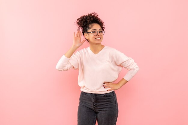 Front view of young woman smiling on pink wall
