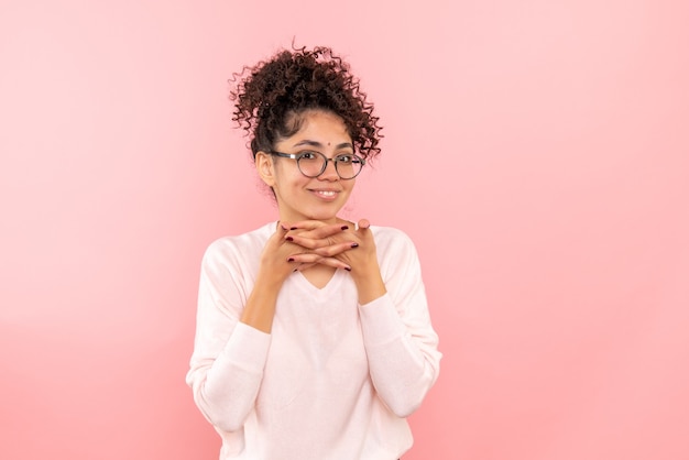 Front view of young woman smiling on pink wall