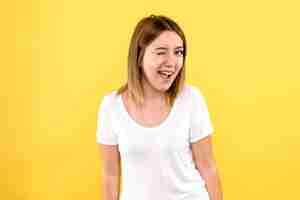 Free photo front view of young woman smiling and winking on yellow wall