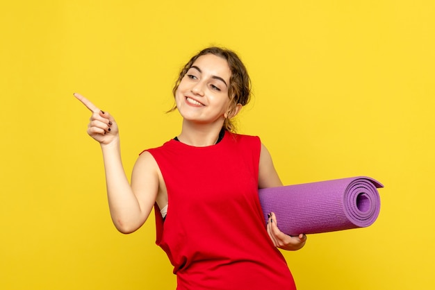 Front view of young woman smiling with purple carpet on yellow wall