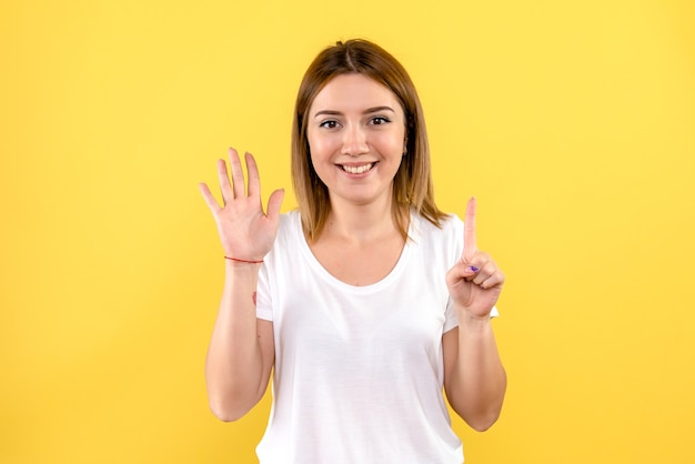 Front view of young woman smiling on yellow wall