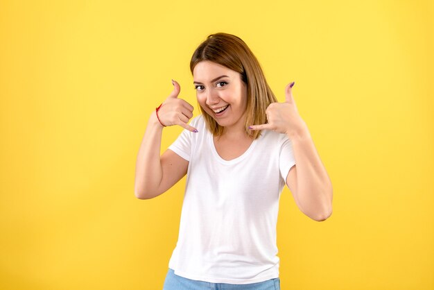 Front view of young woman smiling on yellow wall