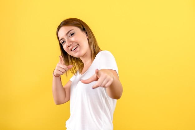 Front view of young woman smiling on yellow wall