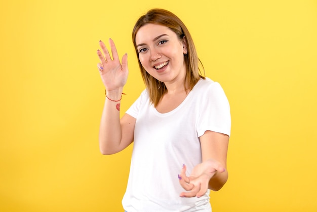 Front view of young woman smiling on yellow wall