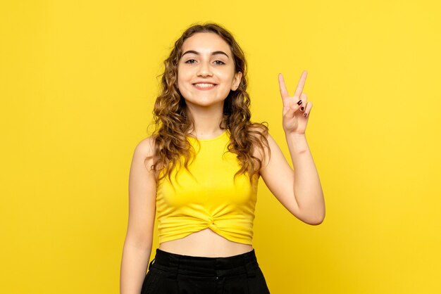 Front view of young woman smiling on a yellow wall