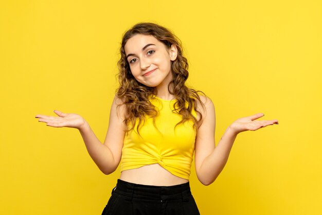 Front view of young woman smiling on a yellow wall