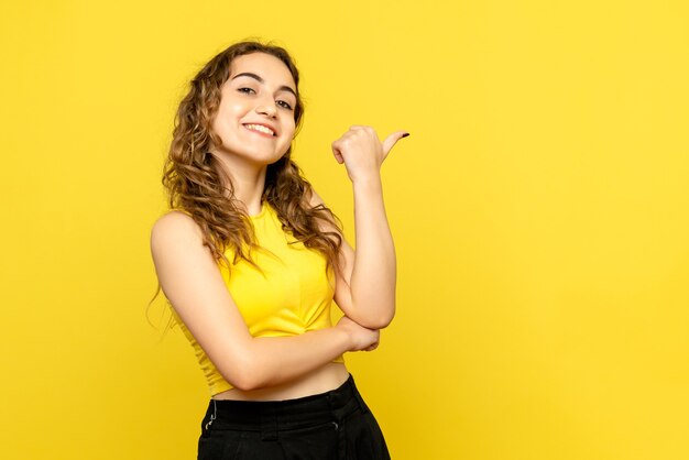 黄色の壁に笑みを浮かべて若い女性の正面図