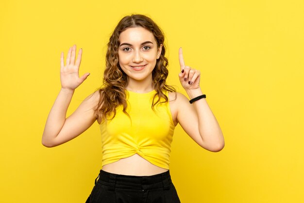 Front view of young woman smiling on yellow wall