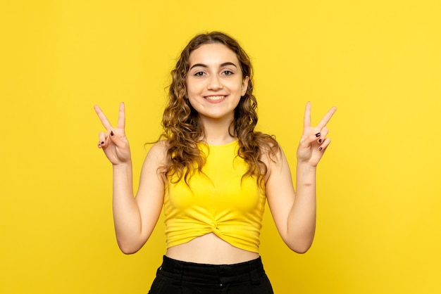 Front view of young woman smiling on yellow wall