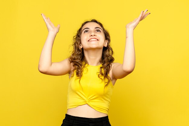 Front view of young woman smiling on yellow wall