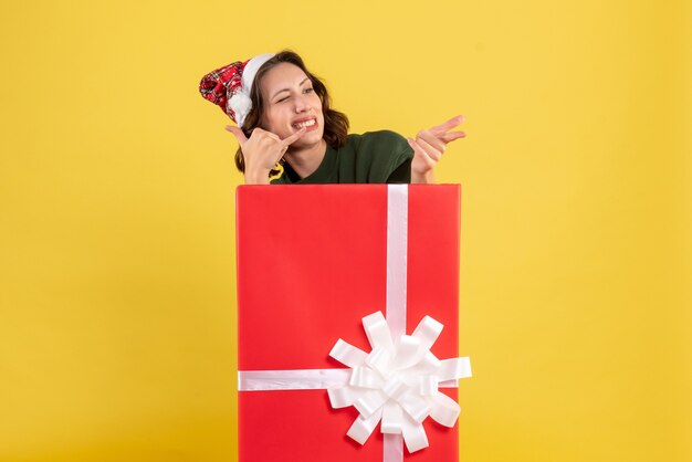 Front view of young woman standing inside box on the yellow wall