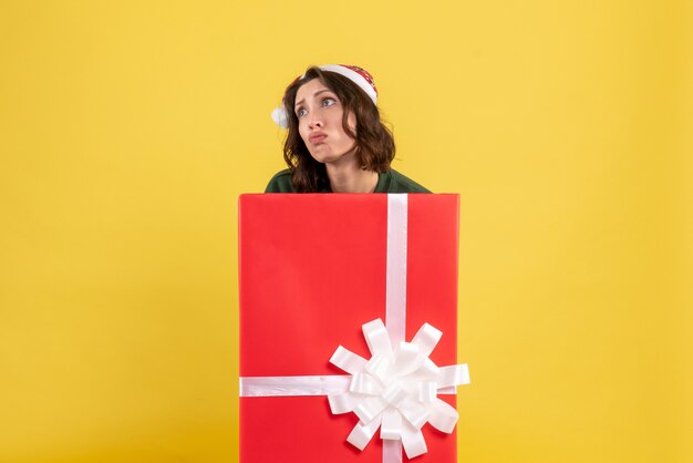 Front view of young woman standing inside box on yellow wall