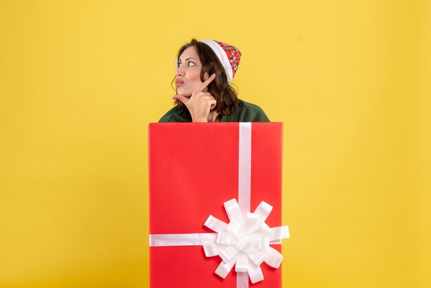 Front view of young woman standing inside box on yellow wall