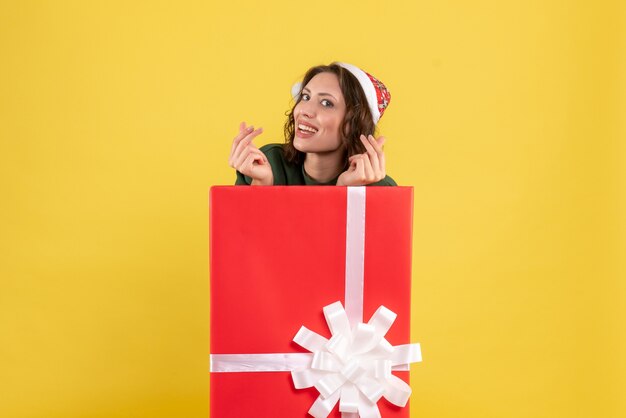 Front view of young woman standing inside box on yellow wall