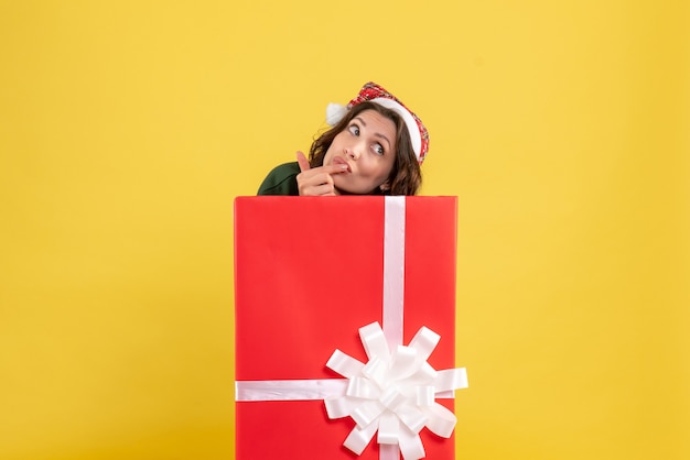 Front view of young woman standing inside box on yellow wall