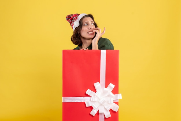 Front view of young woman standing inside box on yellow wall