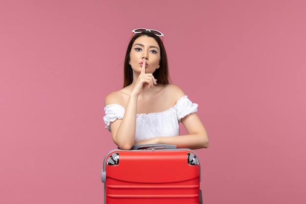 Vista frontale della giovane donna in piedi e si prepara per le vacanze su sfondo rosa chiaro viaggio per mare viaggio all'estero viaggio femminile