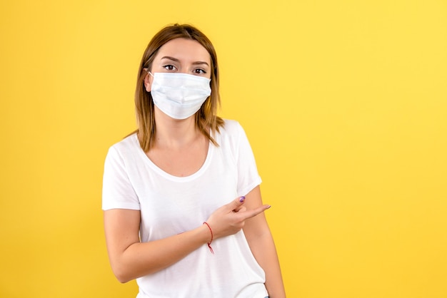 Front view of young woman in sterile mask on a yellow wall
