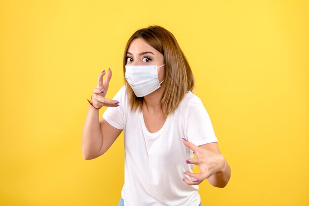 Front view of young woman in sterile mask on a yellow wall