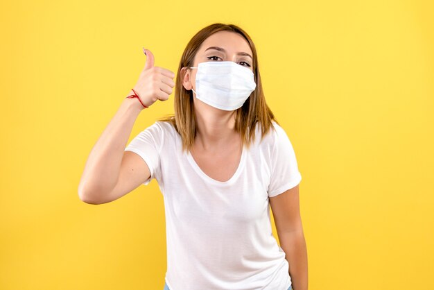 Front view of young woman in sterile mask on yellow wall