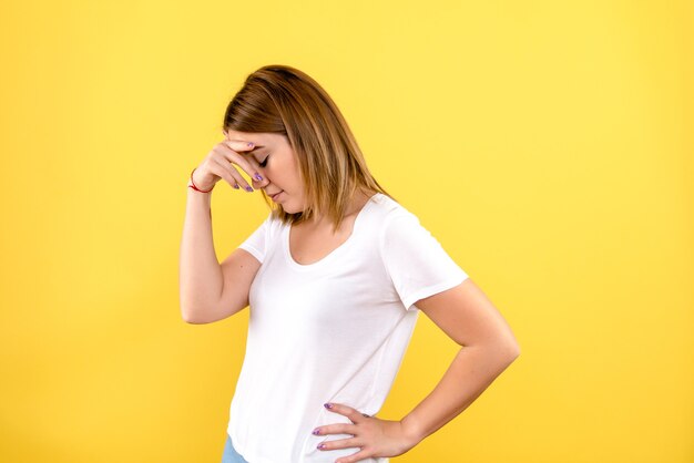Front view of young woman stressed on yellow wall