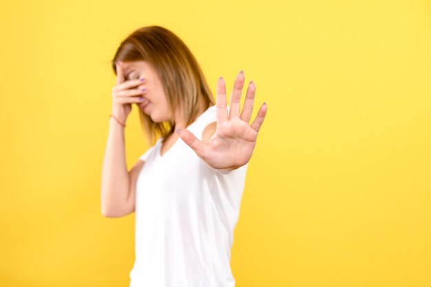 Front view of young woman stressed on yellow wall