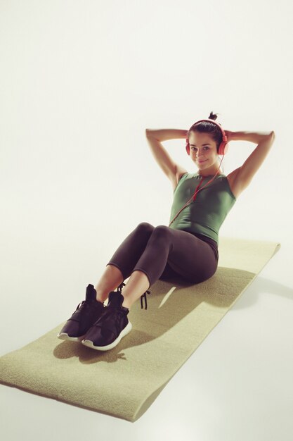 Front view of a young woman stretching body in gymnastics class.