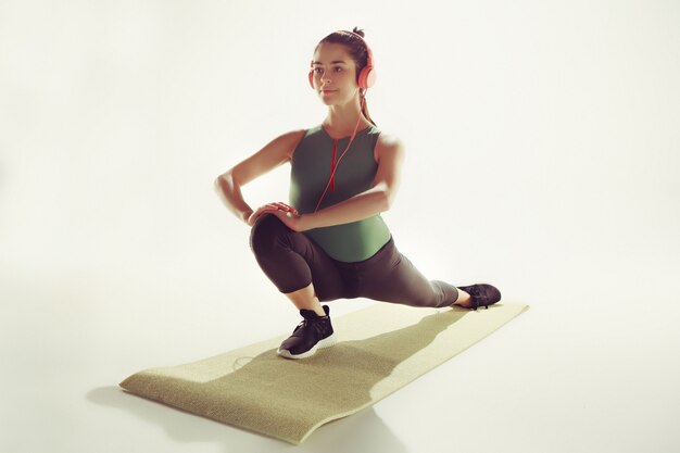 Front view of a young woman stretching body in gymnastics class.