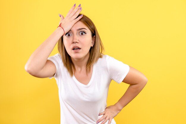 Front view of young woman surprised on yellow wall