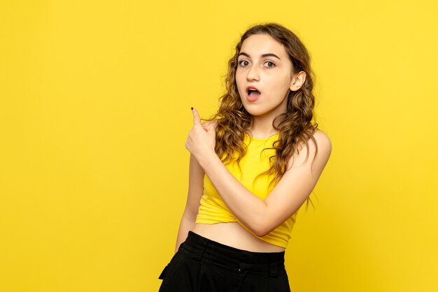Front view of young woman surprised on a yellow wall