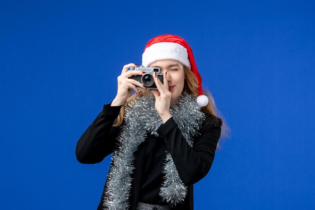 青い壁にカメラで写真を撮る若い女性の正面図