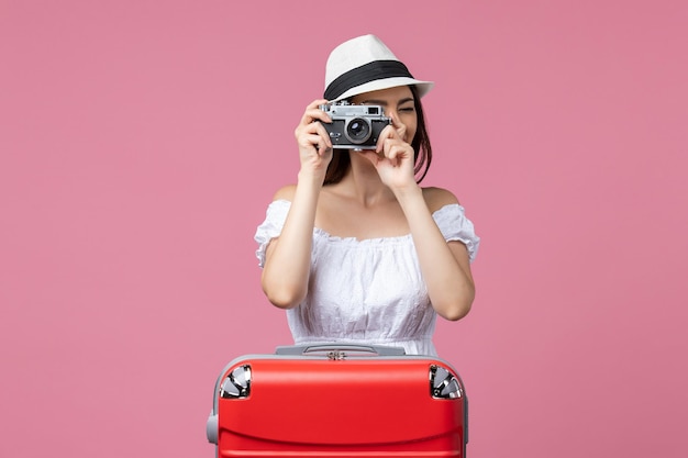 ピンクの壁の夏の色の休暇旅行熱航海で休暇中に写真を撮る正面図若い女性
