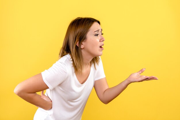 Front view of young woman talking to someone on yellow wall