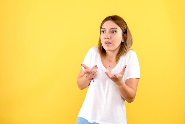 Front view of young woman talking to someone on yellow wall