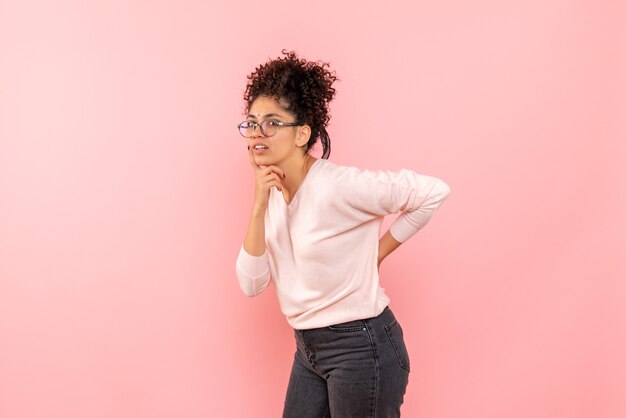 Front view of young woman thinking on a pink wall